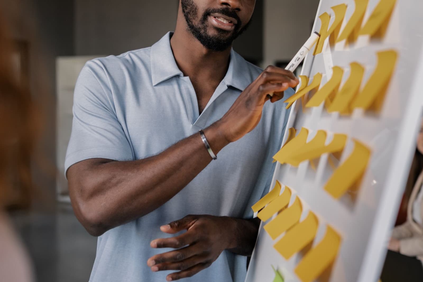 Professionnel présentant une stratégie sur un tableau couvert de post-it